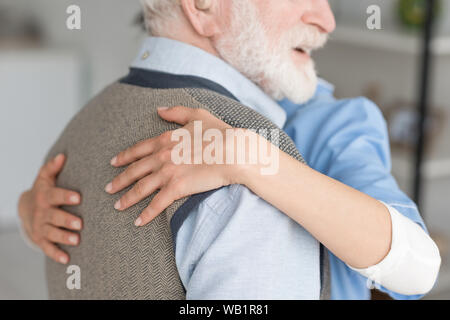 7/8-Ansicht der Krankenschwester umarmen mit grauen Haaren, und lächelnd Mann Stockfoto