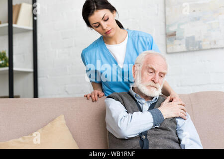 Arzt hinter traurigen älterer Mann, Hand auf seiner Schulter Stockfoto