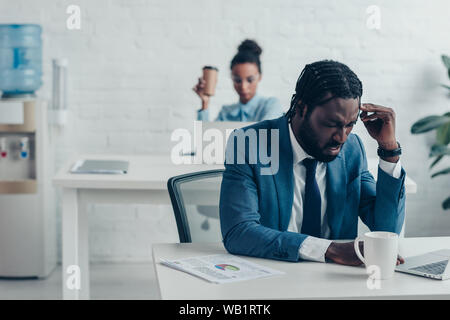 Erschöpft Unternehmer leiden unter Kopfschmerzen, während im Büro sitzen in der Nähe der hübschen Manager Stockfoto