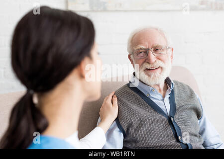 Selektiver Fokus der lächelnden grauhaariger Mann an Krankenschwester suchen Stockfoto