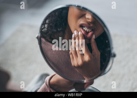 Teilweise mit Blick auf die afrikanische amerikanische Frau im Spiegel während Zahnschmerzen leiden. Stockfoto