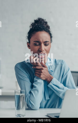 Ziemlich afrikanische amerikanische Geschäftsfrau Leiden von Zahn Schmerzen beim Sitzen am Arbeitsplatz Stockfoto