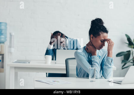 Afrikanische amerikanische Manager sitzen am Arbeitsplatz und leiden unter Kopfschmerzen Stockfoto