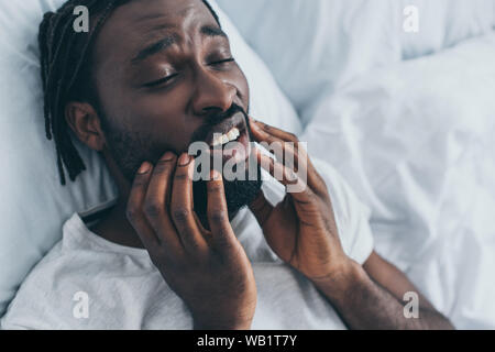 Junge afrikanische Amerikaner leiden unter Kieferschmerzen im Schlafzimmer Stockfoto