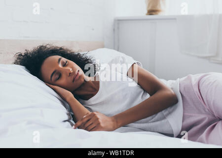 Ziemlich afrikanische amerikanische Frau im Schlafanzug schlafen auf weiße Bettwäsche Stockfoto