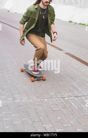 7/8-Ansicht des Menschen in Freizeitkleidung reiten auf Skateboard Stockfoto