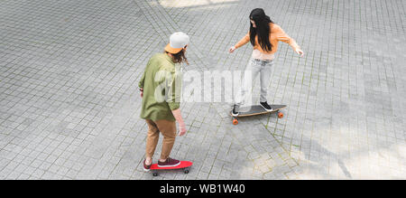 Hohe Betrachtungswinkel und der jungen Frau mit Mann, auf Skateboards auf der Straße Stockfoto