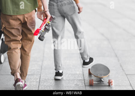 Anzeigen von Mann und Frau zu Fuß auf der Straße mit skateboards 7/8 Stockfoto