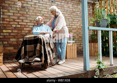 Low Angle View der älteren behinderten Menschen im Rollstuhl in der Nähe von Frau sitzen Stockfoto