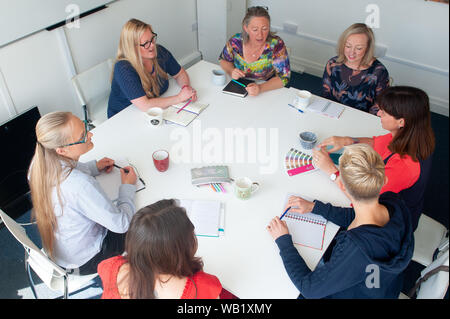 Frauen um eine Tabelle in Diskussion oder Konferenz Stockfoto