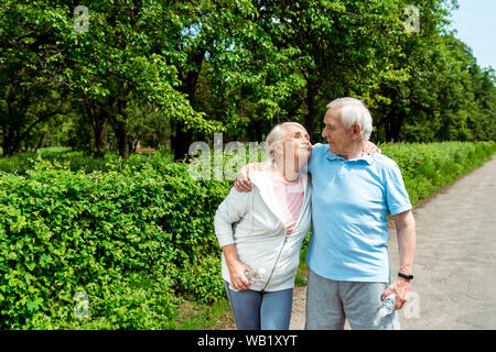 Gerne älterer Mann an Frau suchen und halten die Flasche mit Wasser im Park Stockfoto
