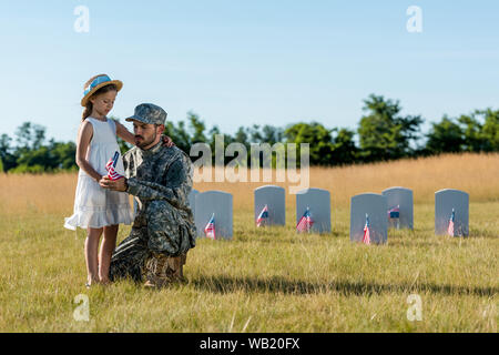 Militärische Mann in Uniform sitzen in der Nähe von Kinder- und Grabsteine im Friedhof Stockfoto