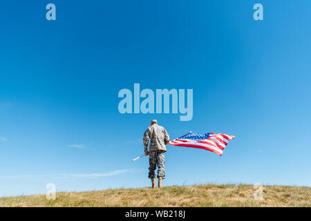 Rückansicht des militärischen Mann in Uniform stehend mit der amerikanischen Flagge mit Sternen und Streifen Stockfoto