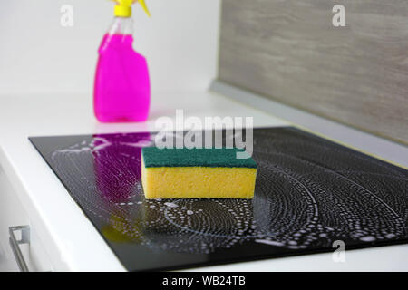 Reinigung der Induktionsherd mit einem Schwamm. Stockfoto