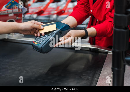 7/8-Ansicht des Kunden die Zahlung per Kreditkarte in der Nähe der Kassierer im Supermarkt Stockfoto