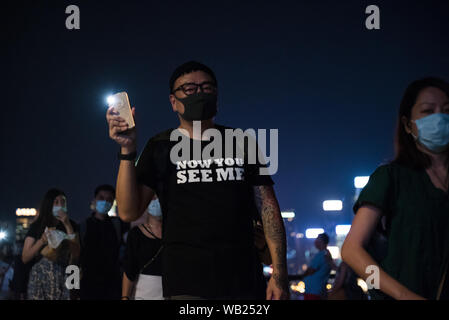 Eine Demonstrantin glänzt sein Telefon Licht Wie geht er mit der menschenkette während der Demonstration. Demonstranten Hände lange Menschenketten in friedlichen Protest gegen die Auslieferung Rechnung zu erstellen. Einige Demonstranten trugen verschiedene Plakate bitten und danken, andere Länder für ihre Unterstützung, während andere auch Ihre Telefon leuchtet als Zeichen der Einheit und des Friedens glänzten. Stockfoto