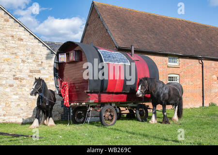 Gypsy Caravan und Pferde an der Seite der Straße vor den Gebäuden in der Nähe von Lighthorne Heide, Warwickshire, England Stockfoto