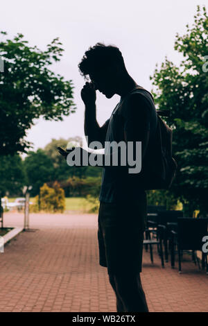 Silhouette der Mann mit Rucksack mit digitalen Geräts außerhalb Stockfoto