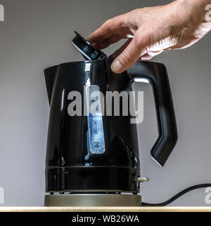 In der Nähe der Hand des Menschen schließen der Deckel eines Schwarzen, mit dem Wasserstand sichtbar durch die Fenster. Stockfoto