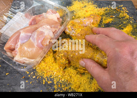 Schließen overhead Shot der Hände Beschichtung Stück eines Mannes von rohem Huhn mit einem trockenen Würzmischung, bereit, für das Kochen. Stockfoto