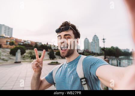 Stattlicher Mann mit Brille, friedenszeichen und unter selfie Stockfoto