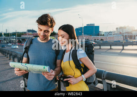 Schöner Mann und die asiatische Frau lächelnd und Suchen auf der Karte Stockfoto