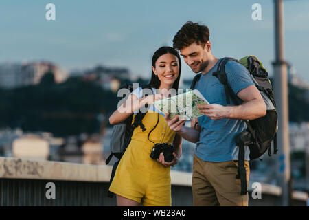 Schöner Mann und die asiatische Frau lächelnd und Suchen auf der Karte Stockfoto