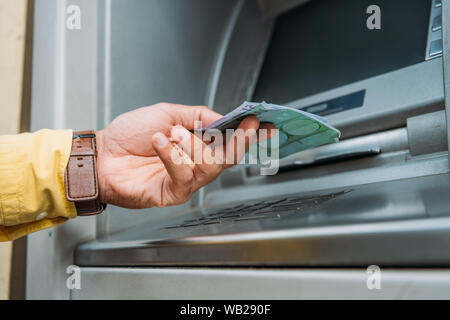 7/8-Ansicht von gemischten Rennen Mann Geld vom Geldautomaten Stockfoto