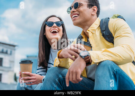 Interracial Freunde mit Rucksäcken auf der Straße sitzen und Kaffee trinken Stockfoto