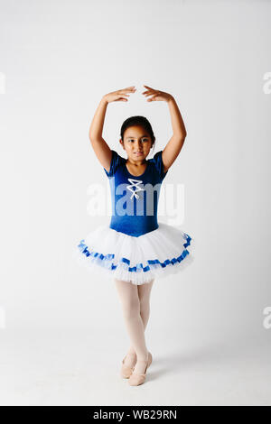 Ein 9-jähriges Mädchen auf ihrem Ballerina Outfit gekleidet. Sie hat Hispanic Ethnizität Features. Sie steht auf ihr Ballett dar. Sie ist mit Blick auf die Kamera. Stockfoto