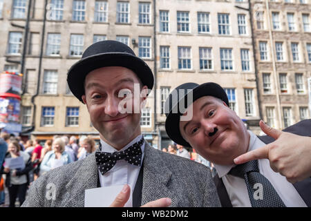 Edinburgh, Schottland, Großbritannien. 23 August, 2019. Darsteller gekleidet, wie Stan Laurel und Oliver Hardy auf der Royal Mile Förderung der glückliche Hund Theater Produktion der Laurel und Hardy Kabarett am Veranstaltungsort 18 während des Edinburgh Fringe Festival. Credit: Skully/Alamy leben Nachrichten Stockfoto