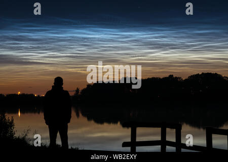 Silhouette einer Person an der leuchtenden Nachtwolken (NLC, Nacht Wolken) in der Nähe von einem See in Holland am Abend suchen Stockfoto