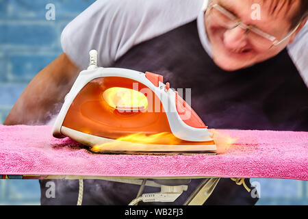 Der Mann vergessen Sie das Bügeleisen von der Power Point zu drehen und fand, daß ein Brand in dem Haus begonnen, weil das Bügeleisen überhitzt war und entzündet, und t Stockfoto