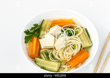 Traditionelle asiatische Suppe mit Tofu, Käse, Nudeln, Karotten und Zucchini auf weißem Hintergrund. Dieses Gericht enthält in der Regel Bouillon und Gemüse Stockfoto