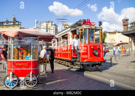 Istanbul, Türkei - 05. August 2019: Die nostalgische Straßenbahn neben einem Warenkorb mit traditionellen Türkischen simit am Ende des berühmten Taksim Istiklal Caddes Stockfoto