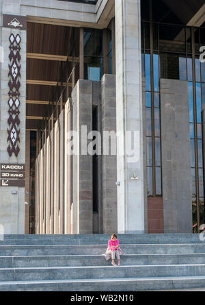 Eine Frau auf der Treppe des Palastes der Republik in Minsk, Weißrussland sitzen. Stockfoto