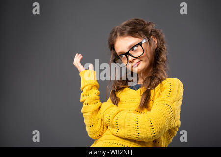 Denken Angry Kid Mädchen gestikulierend die Hand in Brillen Studio auf grauem Hintergrund. Closeup Portrait mit leeren Platz kopieren Stockfoto