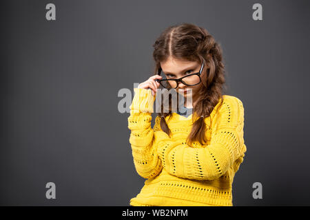 Denken Ernst kid Mädchen mit verschränkten Armen in Brillen studio Suchen auf grauem Hintergrund. Zurück zu Schule. Der Begriff der Bildung. Closeup Portrait Stockfoto