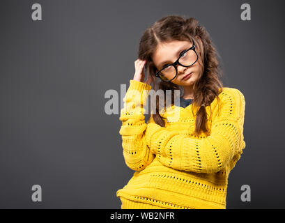 Denken Ernst kid Mädchen Kratzer am Kopf, Brillen Studio auf grauem Hintergrund. Closeup Portrait mit leeren Platz kopieren Stockfoto