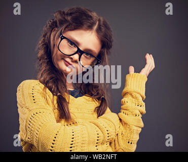 Denken Angry Kid Mädchen gestikulierend die Hand in Brillen Studio auf grauem Hintergrund. Closeup getönten Farben Portrait mit leeren Platz kopieren Stockfoto