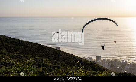 Gleitschirme Start von Cape Town Signal Hill bei Sonnenuntergang über dem Seapoint Vorort auf der Südafrikanischen Atlantik Stockfoto