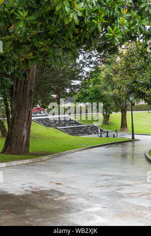 Stein Treppen in einem Stadtpark, umgeben von Bäumen. Durch die Blätter sichtbar Straße mit Autos. In der Nähe der Treppen gibt es einen kleinen Tisch mit Platz für Sh Stockfoto