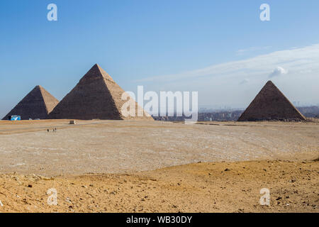 Drei Pyramiden (von links nach rechts) Khufu, Khafre und Menkuare in Ägypten am Morgen mit blauem Himmel. Der Hintergrund ist die Stadt von Gizeh. Drei kleine Stockfoto