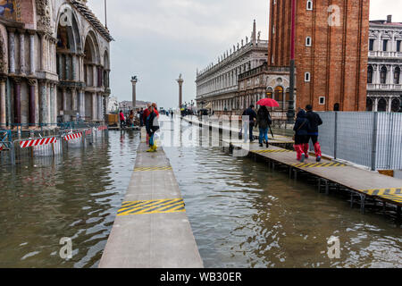 Menschen zu Fuß auf erhöhten Plattformen während der Acqua Alta (hohe Wasser) Fall, Markusplatz, Venedig, Italien Stockfoto