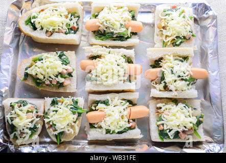 Spinat überbacken mit Käse, Wurst auf Baguette, Französisches Brot Stockfoto
