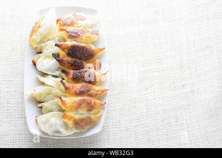 Japanische gebratene Knödel, die einen halbmondförmigen Knödel in asiatischen Restaurants als Vorspeise oder Beilage, Schweinefleisch und Gemüse gefüllt serviert. Stockfoto