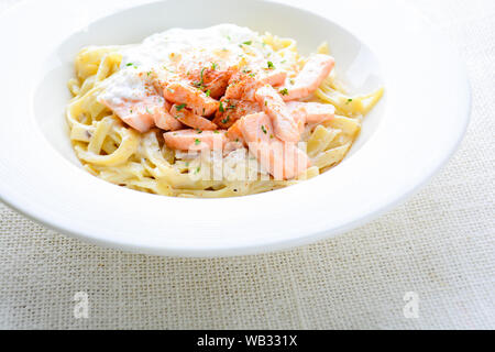 Fettucine mit Lachs, Ei und Parmesan, auf weiße Platte serviert. Stockfoto