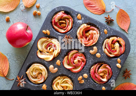 Fach von Apple Rosen in Blätterteig gebacken auf Grau knisterte Holz- Hintergrund mit Herbstlaub und rote Äpfel Stockfoto