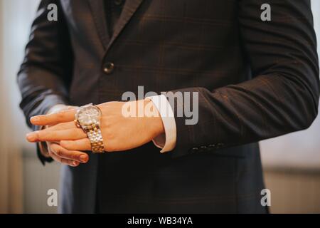 Nahaufnahme der Hand eines Männchens, die einen Klassiker anlegt Teure Uhr vor einem Geschäftstreffen Stockfoto