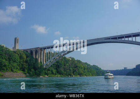 Niagara Falls, Ontario, Kanada: Die Rainbow International Bridge über den Niagara Schlucht, der Regenbogen Carillon Turm, ein Mädchen des Nebels touristische Boot. Stockfoto